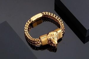Detail of a bold golden lion head pendant on a heavy link stainless steel bracelet