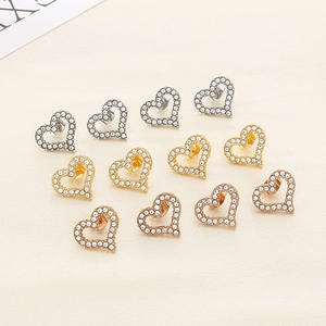 Macro view of heart-shaped hollow earrings with inlaid diamonds in three metallic colors