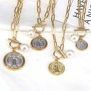 Detailed macro view of vintage religious St. Benedict medal pendants with pearls and OT buckles