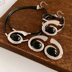 Detailed view of silver spiral jewelry set with black oval stones on a wood surface