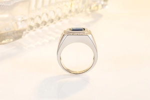 Macro view of men's wide band ring featuring a square blue sapphire with micro-pave crystals