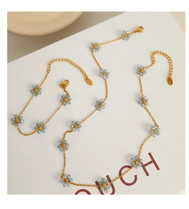 Detail of gold-plated stainless steel necklace and bracelet with blue beaded flowers