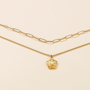 Detail of a gold double-layer necklace with paperclip chain and hollow flower pendant