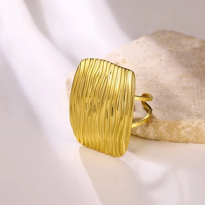 Detail of gold rectangular ring with wavy texture and adjustable open band on silk