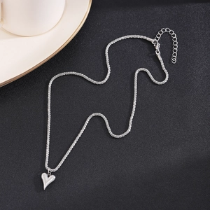 Detailed macro view of silver popcorn chain necklace with a 3D heart pendant on black background