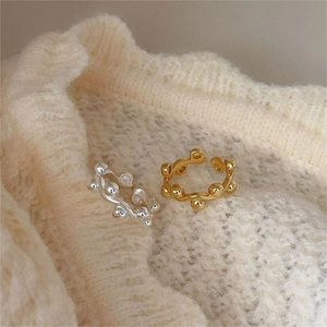 Detail of gold and silver beaded wavy rings on soft knit fabric showing adjustable open band