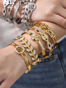 Detail of 18k gold plated bracelets with evil eye and star charms on a female wrist