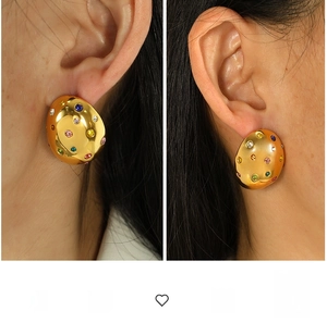 Detailed view of chunky gold-plated earrings with colorful zircon stones on model