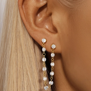 Close-up of elegant gold tassel earrings with clear cubic zirconia on a female model