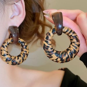 Detail showing oversized round leopard print earrings with resin studs on a model