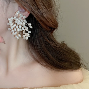 Detailed view of floral firework pearl earrings featuring golden wire on model's ear