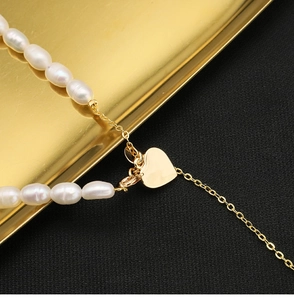 Macro shot of natural white oval pearls and golden heart pendant necklace detail
