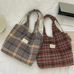 Detail view of two vintage plaid wool tote bags in blue and red tones on white fabric