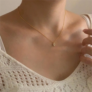 Close-up of a minimalist gold zircon pendant necklace worn on a woman's collarbone