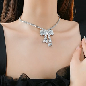 Close-up of sparkling silver bow necklace with pavé crystals on elegant model neckline