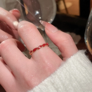 Close-up of gold-plated twisted ring with red enamel details on a female model finger