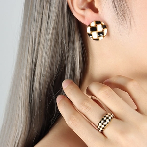 Set orecchini e anello dorati con motivo a scacchi bianco e nero indossati da modella