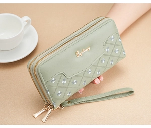 Detail of green long wallet with quilted pattern and floral print held by hand