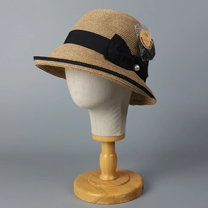 Detail of straw sun hat with black bow, pearl accent and UPF 50+ protection tag