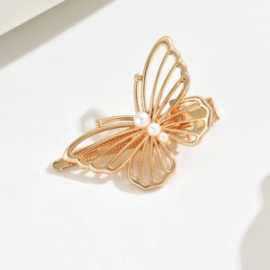 Detailed close-up of a golden hollow butterfly hair clip with inlaid white pearls