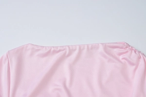 Dettaglio dello scollo dell'abito a pieghe rosa con cuciture rifinite e trama del tessuto