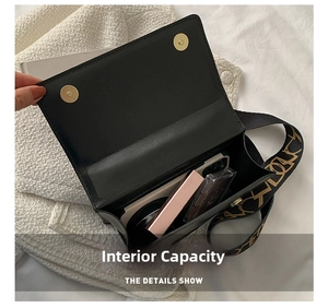Detail view of the black crossbody bag interior capacity with wide embroidered strap