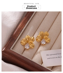 Detail of floral titanium steel earring with pear-shaped zircon and gold finish