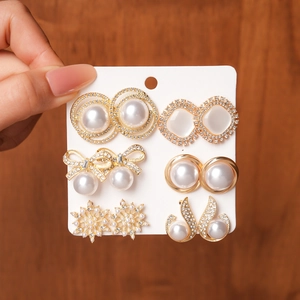 Detailed view of six-pair earring set featuring faux pearls, rhinestones and golden motifs