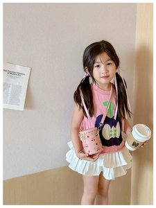 Pink cylinder kid cross-body bag featuring cherry prints and gold chain on young model