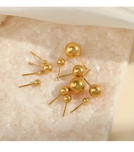 Detailed close-up of matte gold sphere stud earrings in various sizes on a white stone