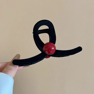 Detail shot of the black flocked hair claw with a vibrant red bead accent decoration