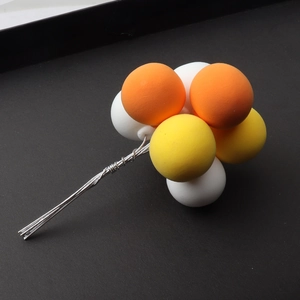 Detailed close-up of white, orange, and yellow clay balloon cake toppers on metal wires