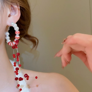 Elegant red and white beaded hoop earrings with long tassels on a professional model