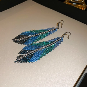 Macro detail of leaf-shaped earrings with blue-green gradient rhinestones and crystals