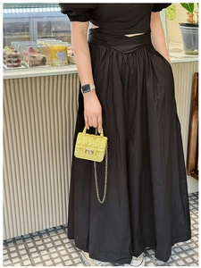 Detailed view of yellow quilted mini jelly bag with gold chain strap in a cafe setting