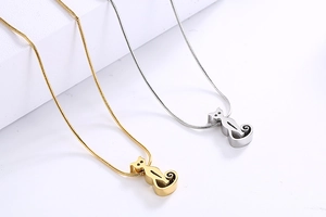 Macro shot of gold and silver cat-shaped necklaces with fine snake chains on white surface