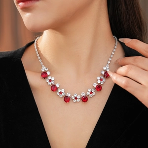 Close-up of red and white zircon flower necklace on a model wearing black velvet