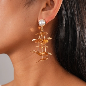 Detailed close-up of golden ginkgo leaf fringe earrings with white pearls on a model