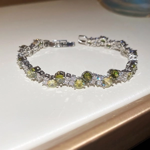 Close-up of sparkling green and clear cubic zirconia stones on twisted silver bracelet