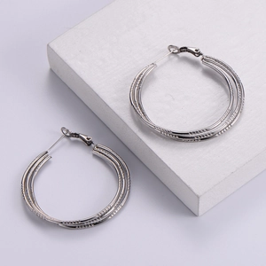 Minimalist silver steel triple-layered textured hoop earrings on a clean white display