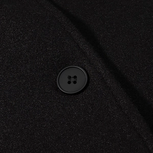 Détail d'un bouton noir à quatre trous sur un tissu de laine de qualité pour manteaux