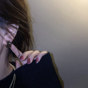 Gros plan de boucles d'oreilles C géométriques asymétriques en or et noir sur modèle