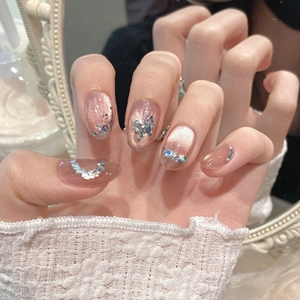Détail d'ongles rose œil de chat avec papillon en cristal 3D et décorations de strass