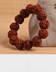 Close-up of deep red Rudraksha beads with brain-like textures on a ceramic vase