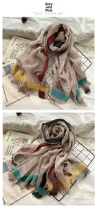 Detail of dusty pink wool scarf showing colorful stripe pattern and frayed fringe edges
