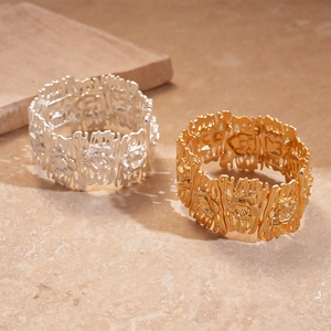 Matte gold and silver hollow flower geometric cuffs on textured stone surface