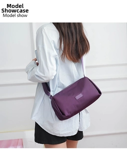 Modelo luciendo un bolso bandolera cilíndrico violeta oscuro de nailon ligero y suave