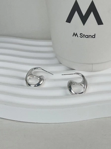 Detail of silver irregular hollow stud earrings with polished mirror finish on white stand