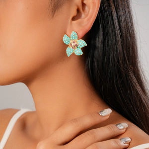 Close-up of a bohemian gold flower stud earring with turquoise and pink bead accents