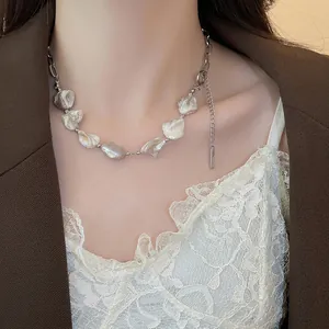 Collana di perle barocche e catena d'argento indossata da una modella in stile chic